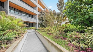 Um edifício moderno com um caminho central ladeado por vegetação exuberante e plantas floridas.