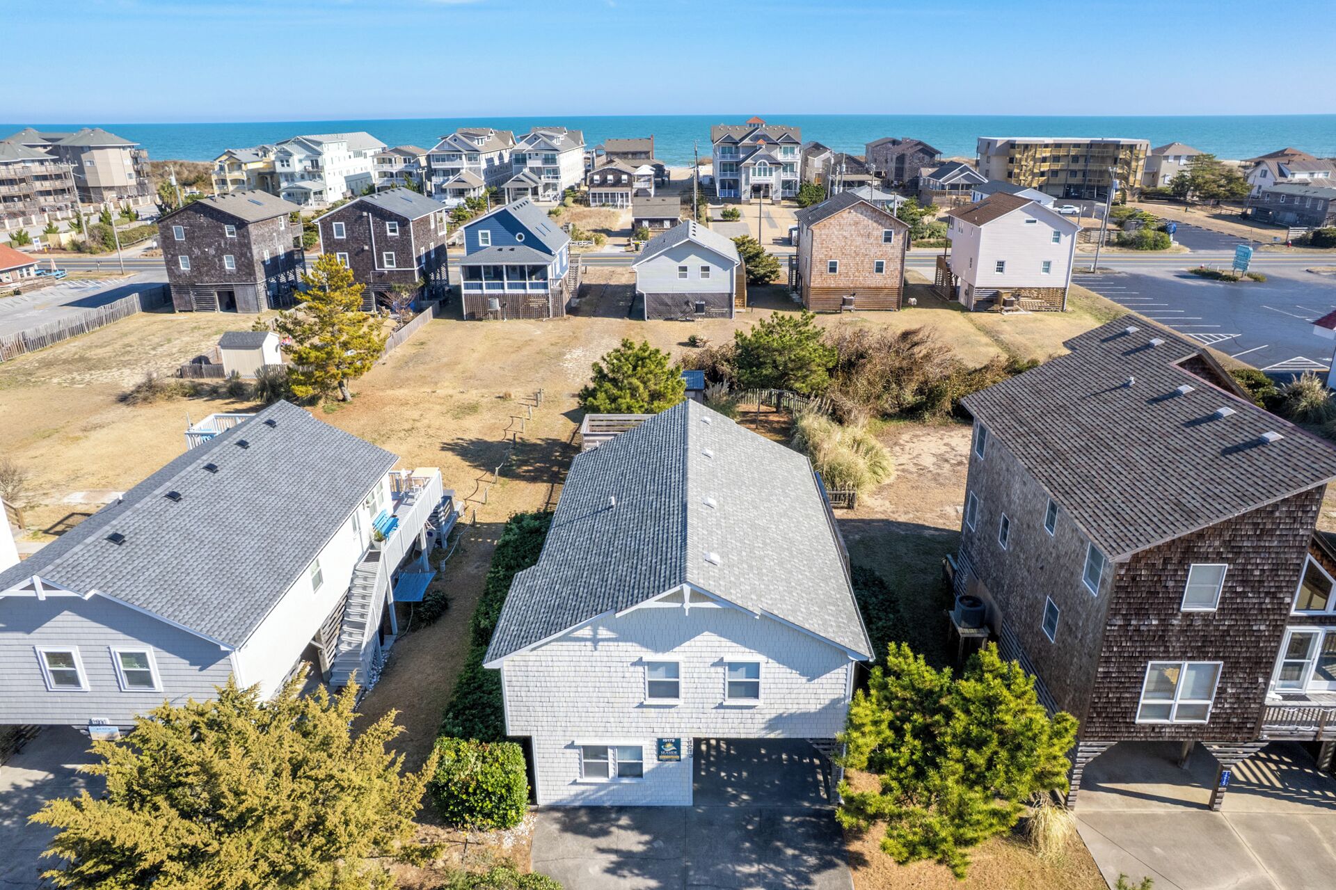 A residential area with houses, a parking lot, and a view of the ocean.