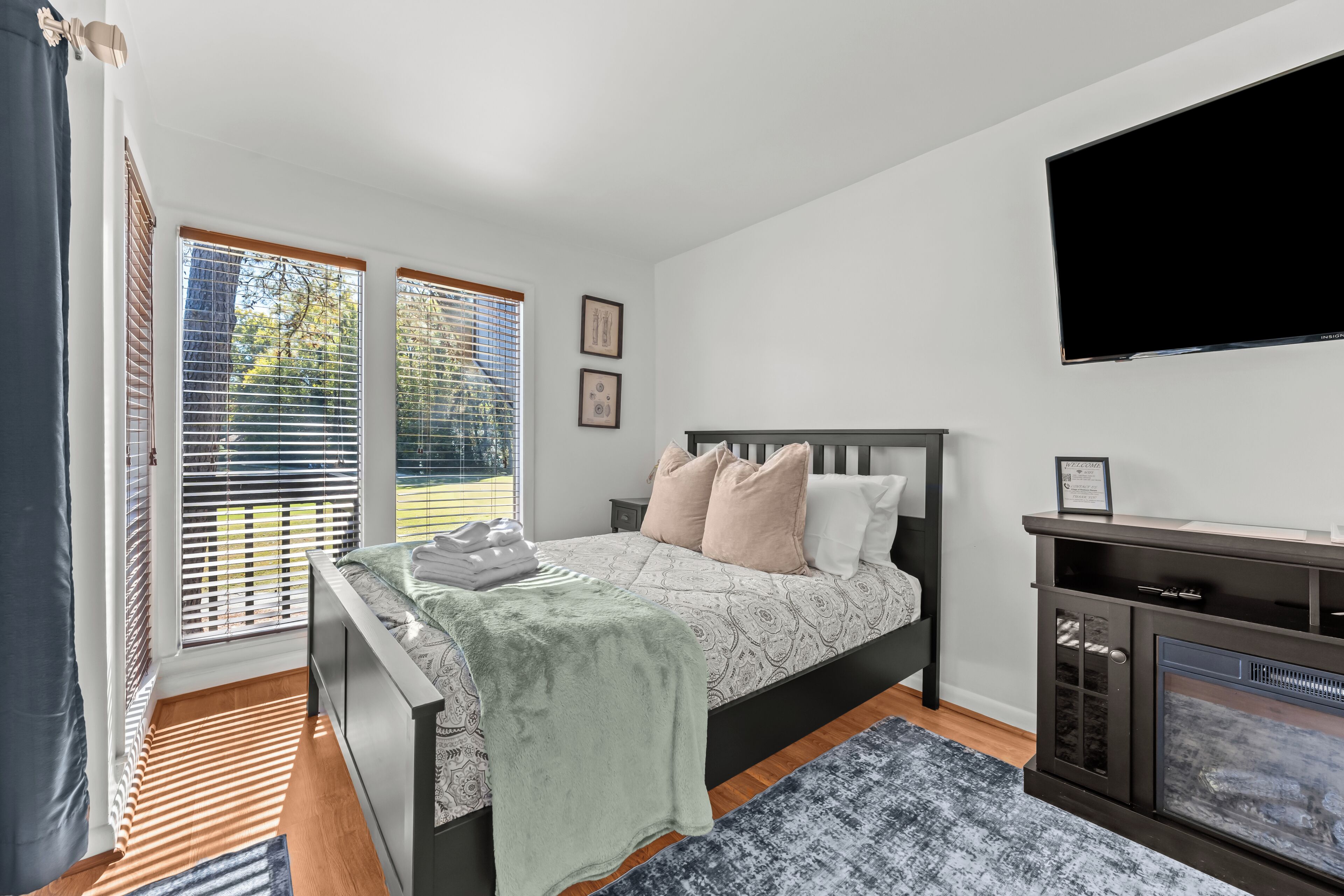 A bedroom with a bed, a television, and a fireplace.