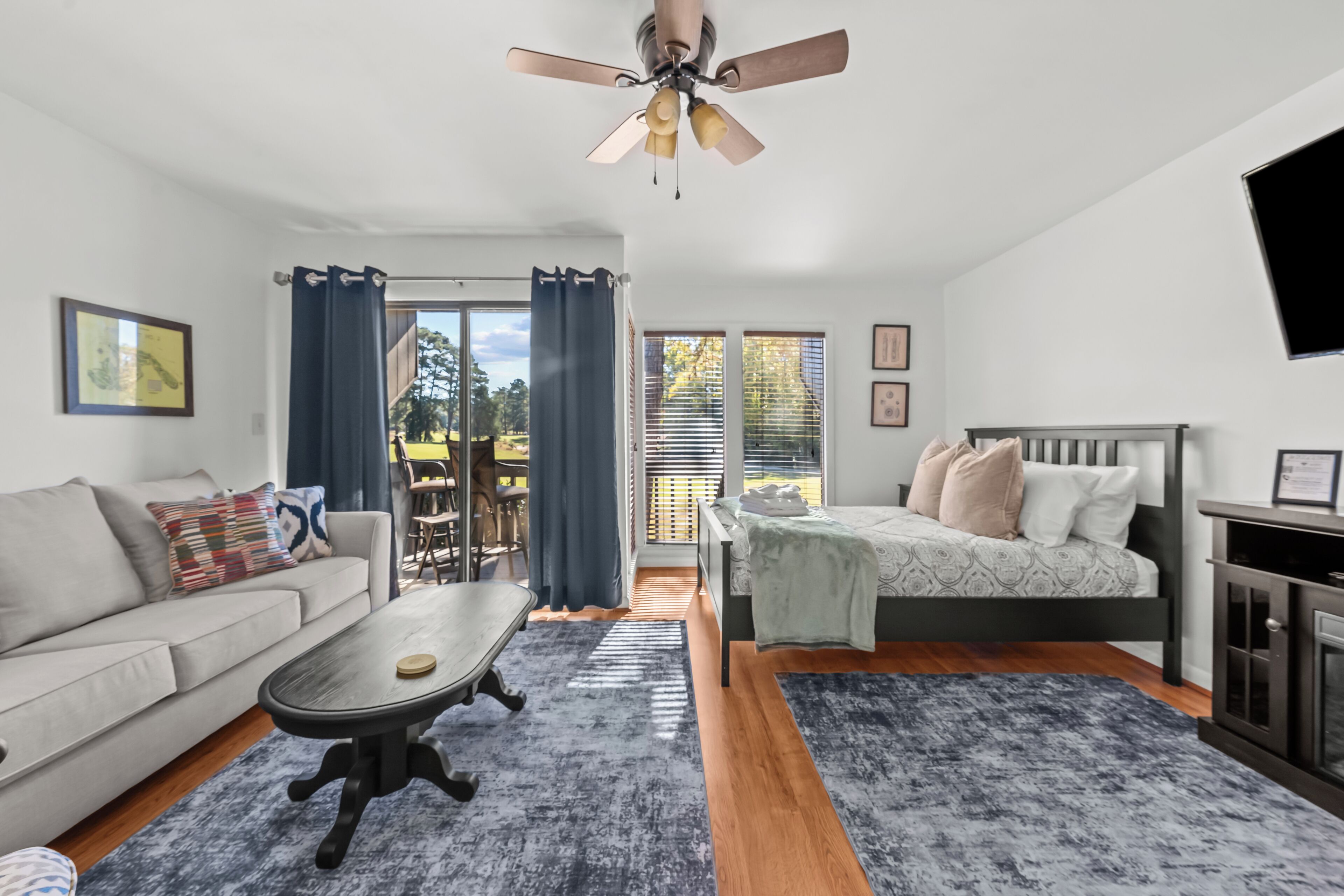 Ein modernes Schlafzimmer mit Bett, Sofa, Couchtisch und Deckenventilator.