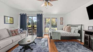 Ein modernes Schlafzimmer mit Bett, Sofa, Couchtisch und Deckenventilator.