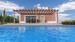 A poolside building with a pergola, a glass door, and a patio with chairs. - Blue Heaven Luxury V5 (Porches)