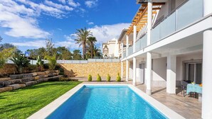 A modern pool area with a clear blue pool, stone walls, and a well-maintained lawn. - Luxury Vau Beach Villa with Private Heated* Pool (Portimão)