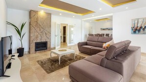 A modern living room with a fireplace, a sofa set, a coffee table, and a large mirror. - Luxury Vau Beach Villa with Private Heated* Pool (Portimão)