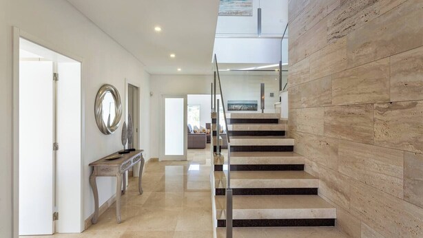 A modern interior with a staircase leading to an upper level, a console table with decorative items, and a large mirror on the wall. - Luxury Vau Beach Villa with Private Heated* Pool (Portimão)