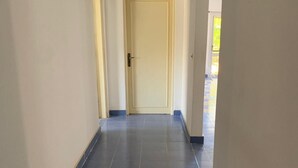 A hallway with dark blue tiles, a white door, and a ceiling light.