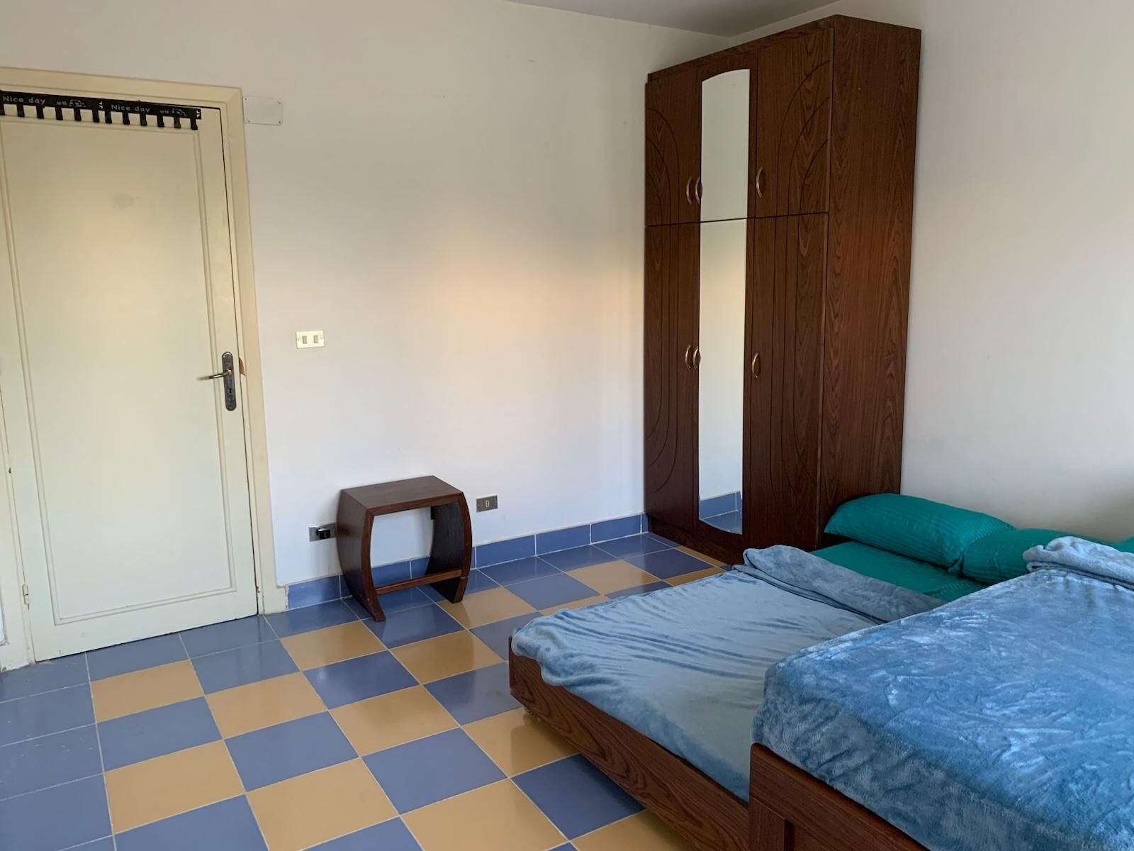 Un dormitorio con cama, armario y un taburete pequeño.