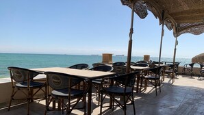 An outdoor seating area with tables and chairs, overlooking the sea.