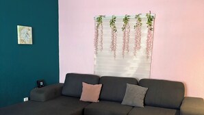 A living room with a sectional sofa, a small black table, and a decorative hanging plant.
