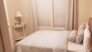 Una camera da letto con un letto, un comodino con una lampada e una finestra con persiane.