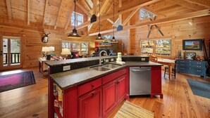 A spacious kitchen with wooden beams, a central island, and a red cabinet. - Log Cabin Near Skiing–Sugars Cozy Cabin (Sugar Mountain)