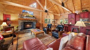 A cozy log cabin interior with a stone fireplace, leather furniture, and wooden beams. - Log Cabin Near Skiing–Sugars Cozy Cabin (Sugar Mountain)