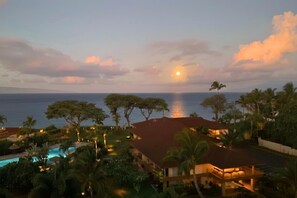 Ein Resort mit Pool, Palmen und Blick auf den Sonnenuntergang.
