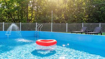 Piscina com escada, um boi-de-água vermelho e cadeiras de sol.