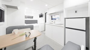 A compact, modern kitchenette with a refrigerator, sink, and a small dining area with a table and chairs. - Gangneung Pinehill Park Pension&caravan (Gangneung)