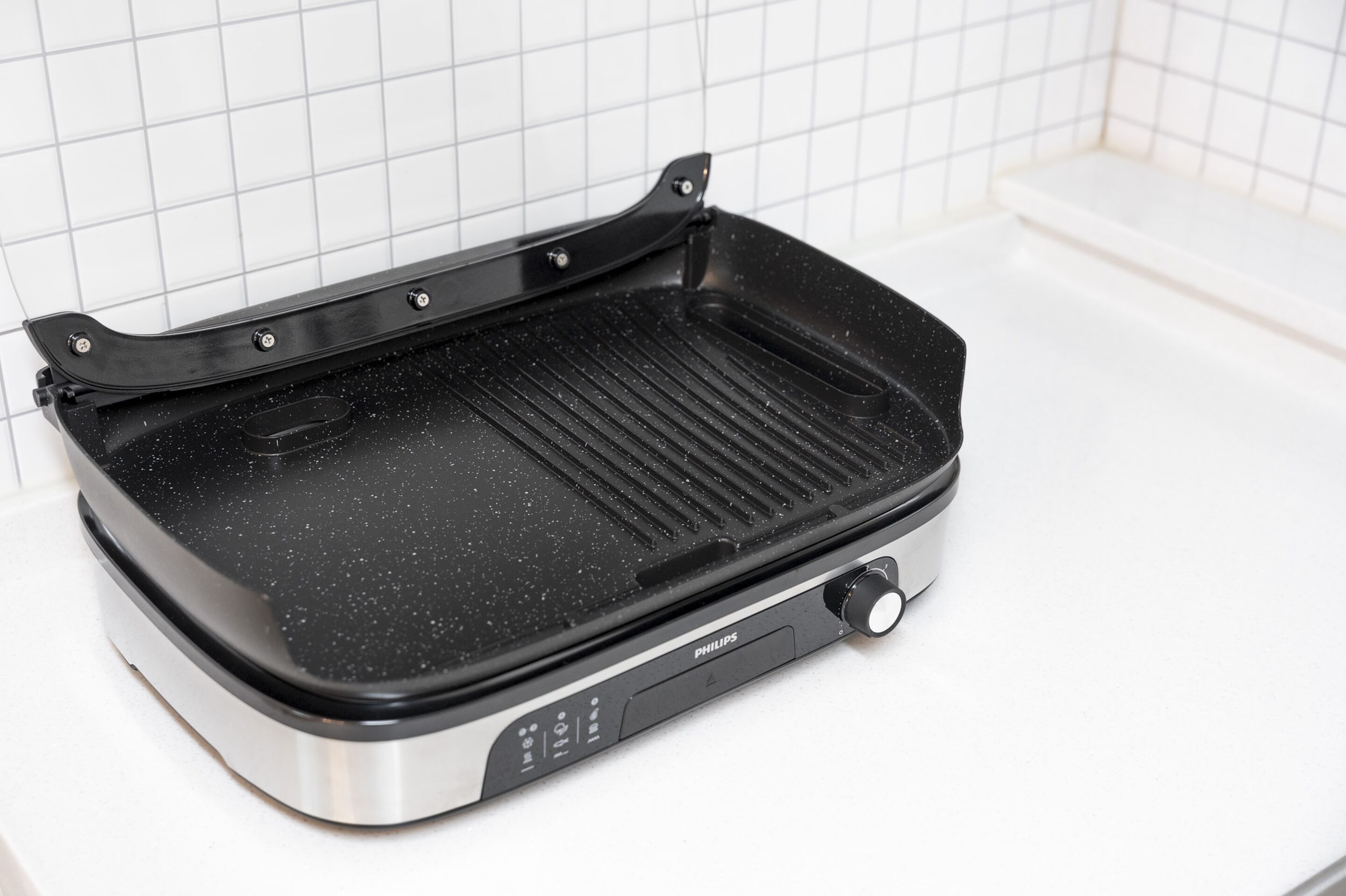 Ein schwarzer und silberner Elektrogrill mit Bedienfeld und Tragegriff.