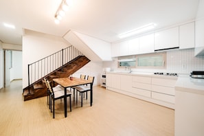 Una cocina moderna con armarios blancos, una mesa de comedor de madera y una escalera con barandillas negras.