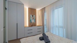 Un dormitori amb llit, un quadre a la paret, un armari i una finestra amb cortines.