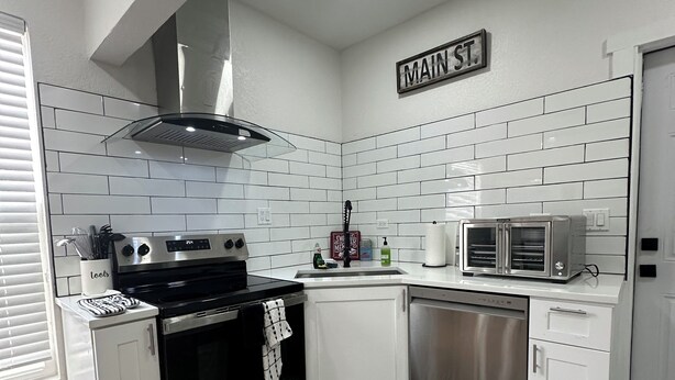 Een moderne keuken met witte metrotegels, roestvrijstalen apparatuur en een bord met 'MAIN ST.'