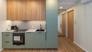 Una cocina compacta con armarios de madera, un lavamanos y un horno empotrado.