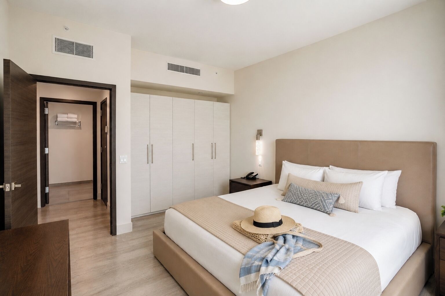 A hotel room with a bed, a nightstand, a wardrobe, and a door leading to another room.