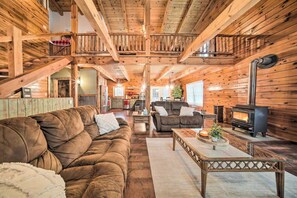Ein gemütliches Blockhaus-Interieur mit einer Holztreppe, einem Kamin und einem Wohnbereich mit Sofas und einem Couchtisch.