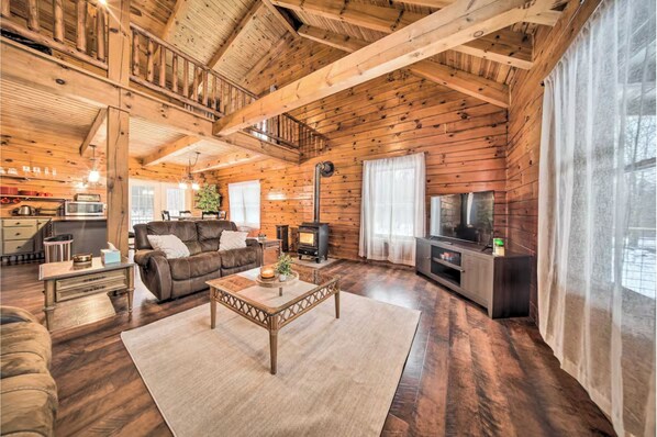 A cozy cabin interior with a wooden interior, a fireplace, a sofa, a coffee table, and a television.