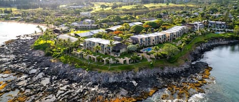 Eine Luftaufnahme eines Küstenresorts mit mehreren Gebäuden, einer felsigen Küstenlinie und klarem Wasser.