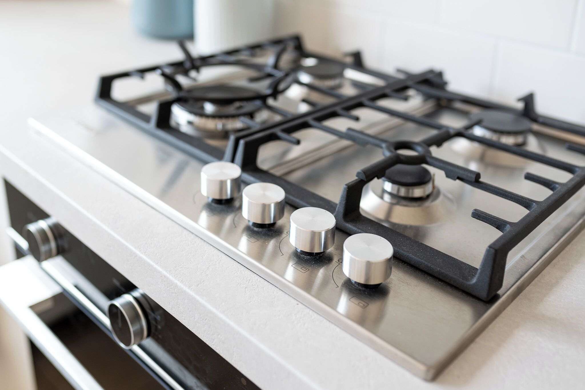 A kitchen with a stainless steel stove and oven, featuring four burners and a control panel with knobs.