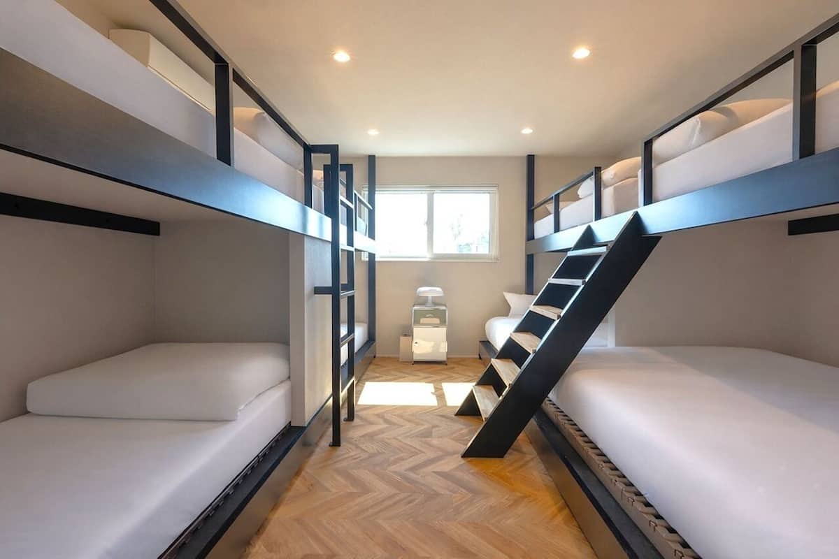 Un dormitorio con literas, una ventana y una mesita de noche.