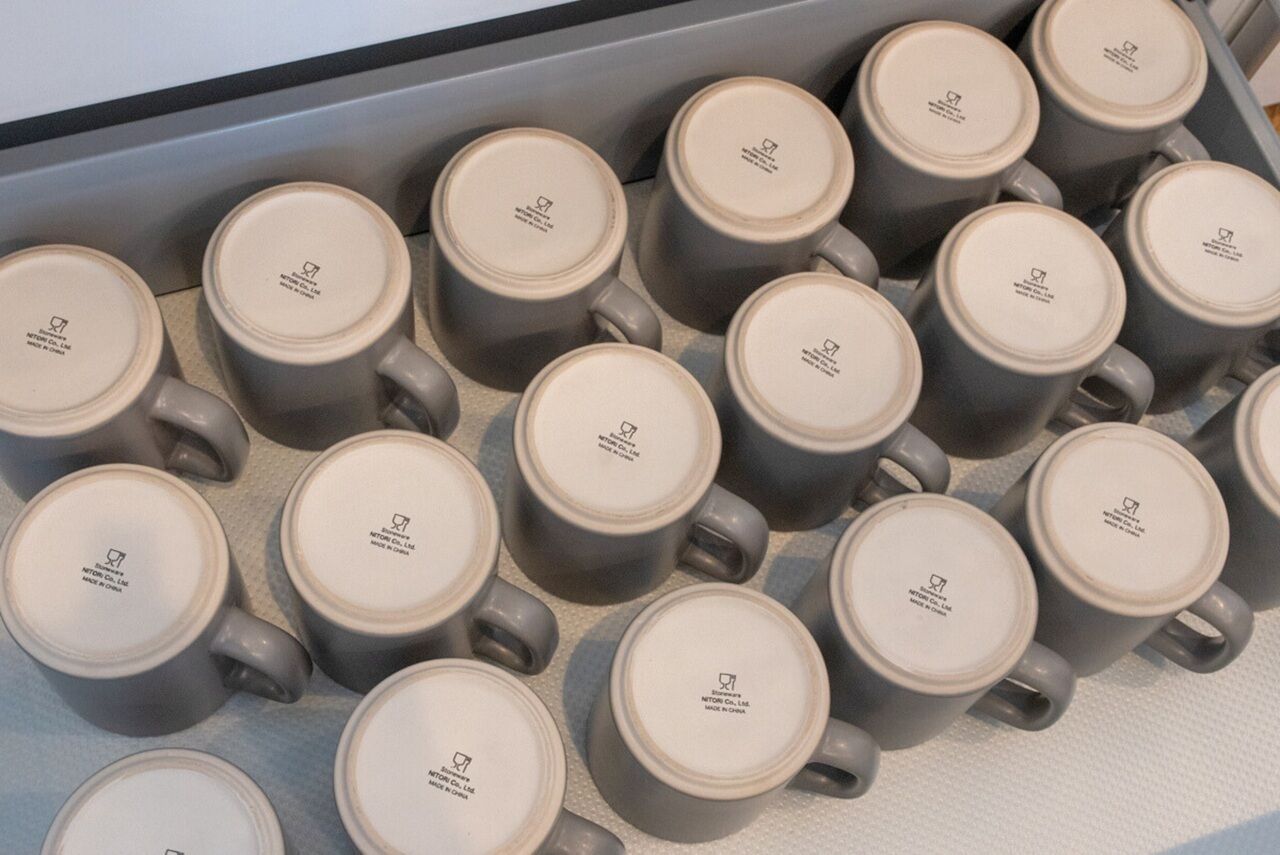 A display of grey ceramic mugs arranged in rows on a shelf.