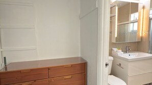 Uma casa de banho moderna com um lavatório de madeira, uma sanita branca e um lavatório com espelho.