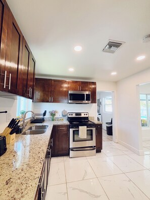 A modern kitchen with wooden cabinets, stainless steel appliances, and a granite countertop.