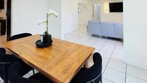 Ein moderner Essbereich mit einem Holztisch, schwarzen Stühlen und einer Kronleuchter.