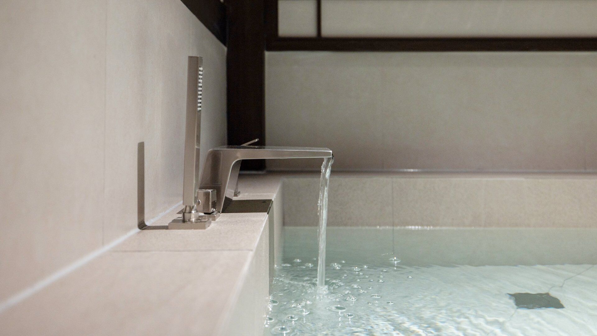 A modern bathroom with a bathtub, a faucet, and a showerhead.