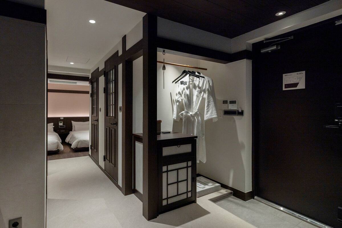 Habitación de hotel con cama, mesita de noche y bata colgada.