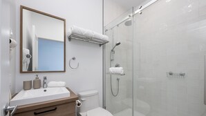 Une salle de bain moderne avec une douche à parois de verre, un lavabo blanc et des toilettes.