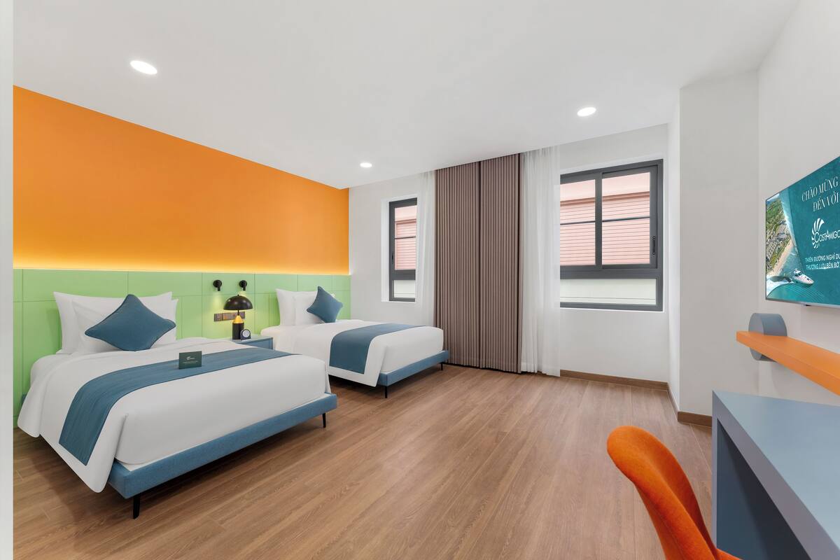 Une chambre d’hôtel avec deux lits, un bureau et une chaise.