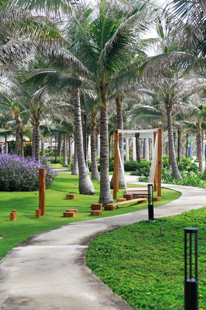 A pathway lined with palm trees and a wooden pergola structure. - Amigo Sol Phan Thiet (Ham Thuan Nam)
