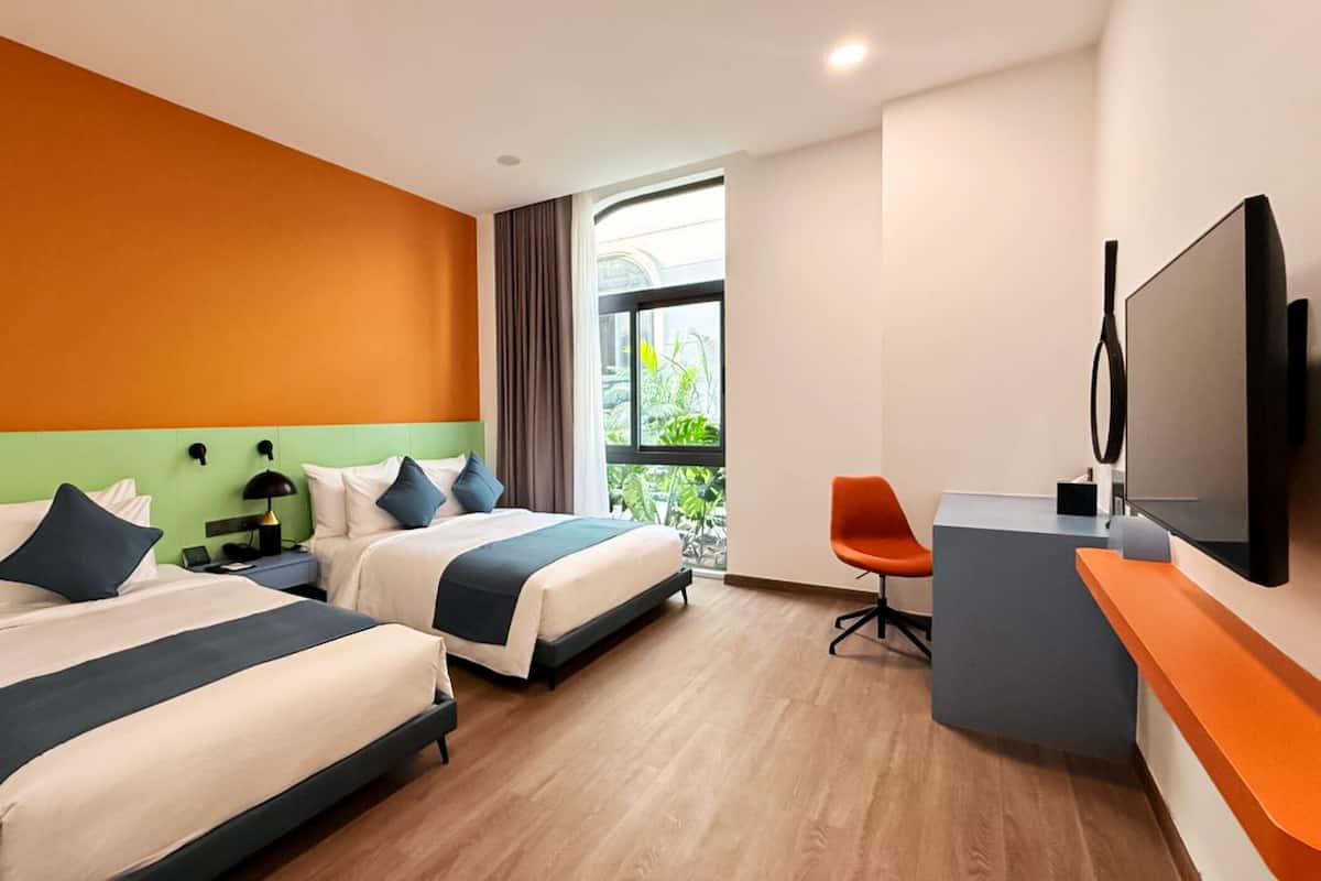 Une chambre d’hôtel avec deux lits, un bureau, une chaise et un téléviseur.