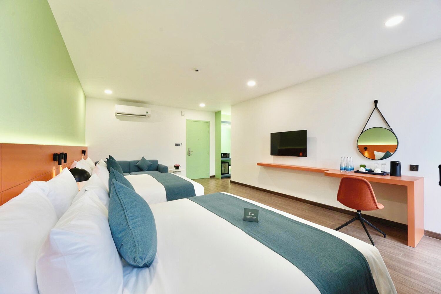 Una habitación de hotel con dos camas, un escritorio, un televisor y un espejo.