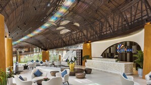 Um hall amplo com assentos modernos, balcão de recepção e teto decorativo.