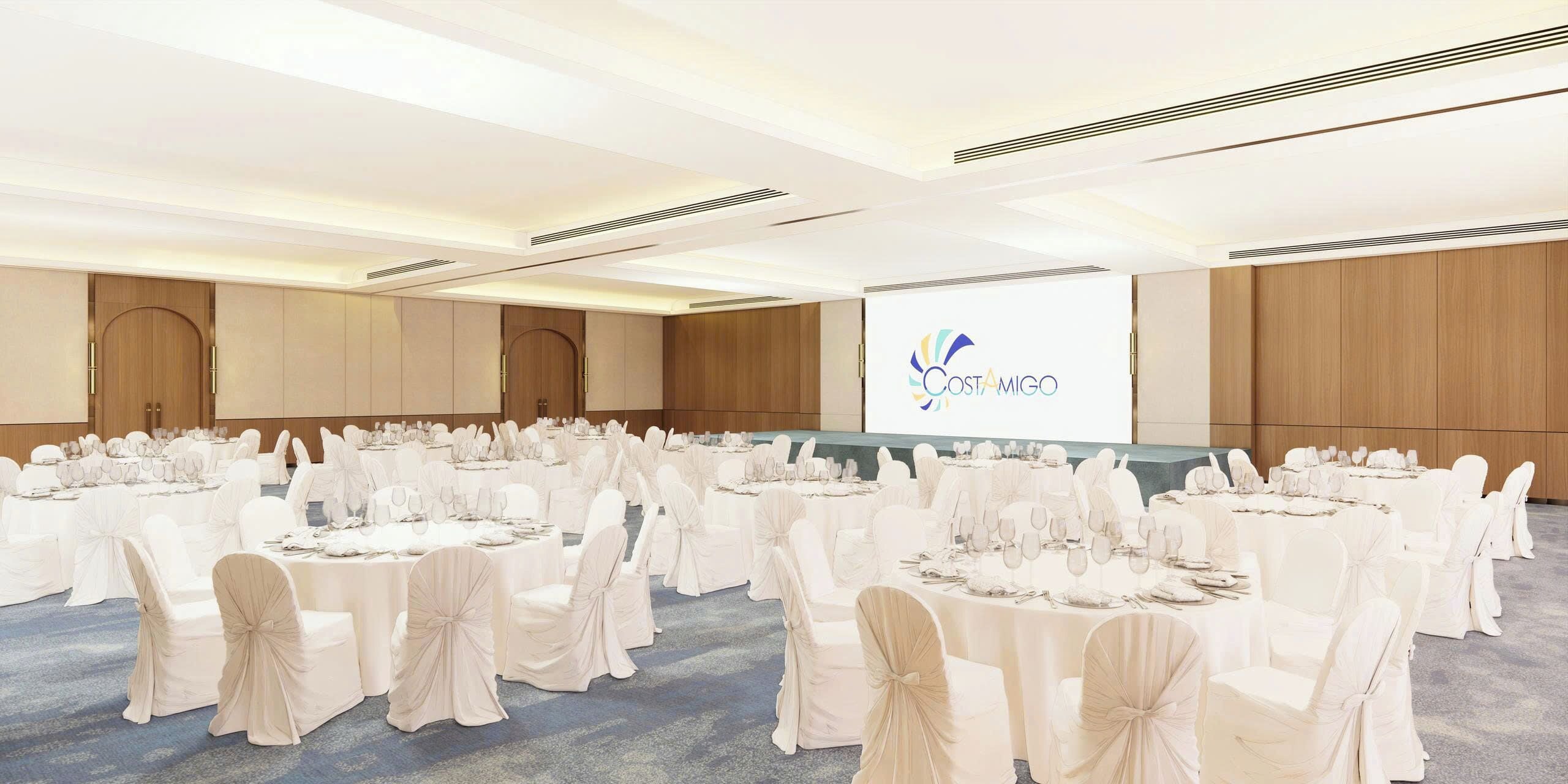 A conference room with round tables, white chairs, and a presentation screen.