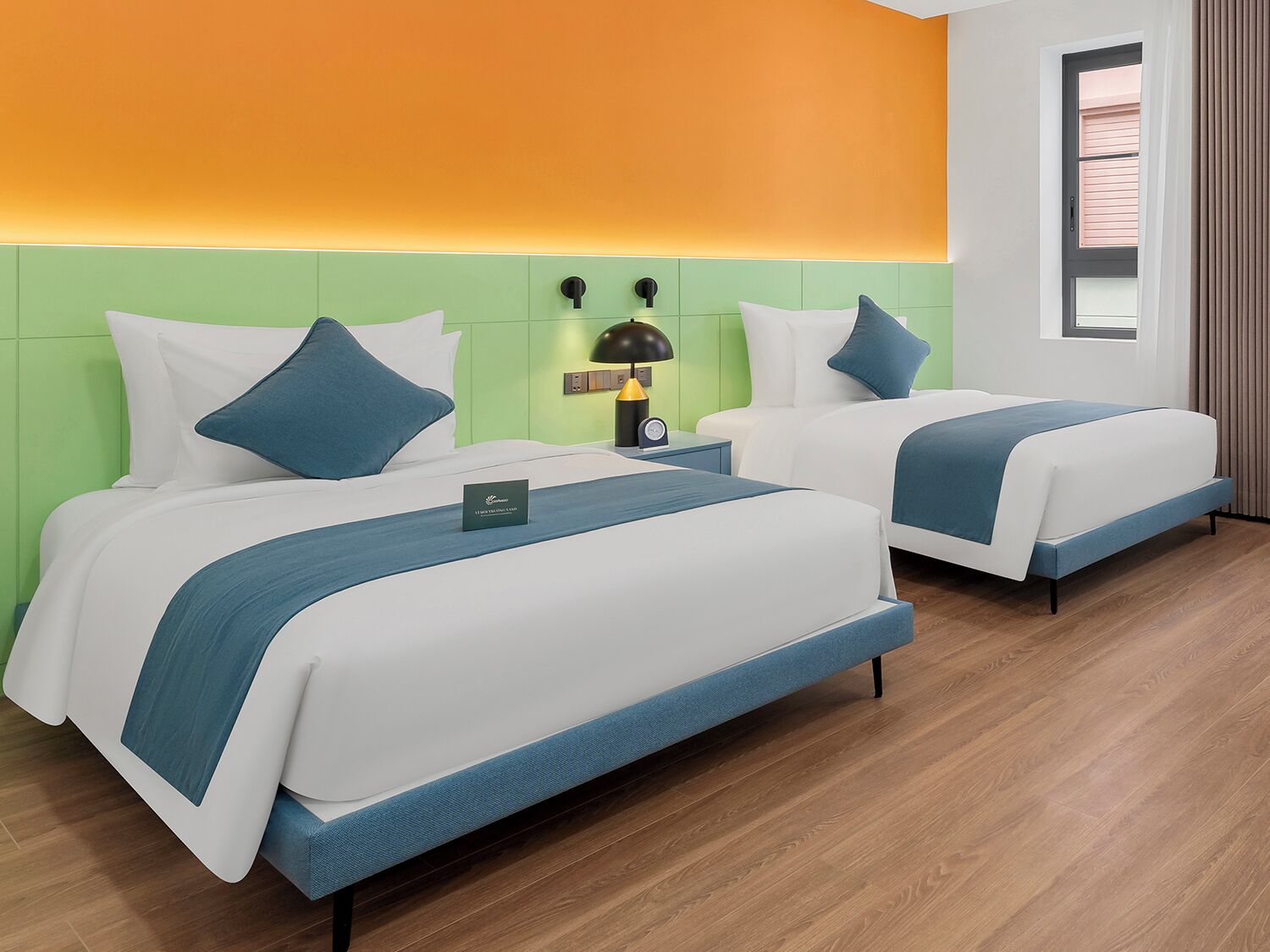 Habitación de hotel con dos camas, una mesita de noche con lámpara, una ventana con persianas y una pared verde decorativa.