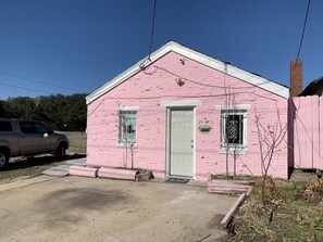 A pink single-story house with a white door and two windows, a small porch, and a number '2908' on the wall. - Pink Flamingo - Pet Friendly, Beach Side, Wi-Fi (Norfolk)