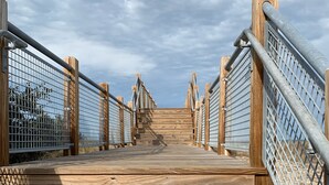Un pasillo de madera con barandillas de metal que conduce a una plataforma elevada.