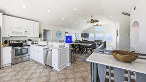 A spacious kitchen with white cabinets, a stainless steel oven, and a large island with a sink. - Anthem of the Sun | Oceanfront | Private Pool and Hot Tub (Virginia Beach)