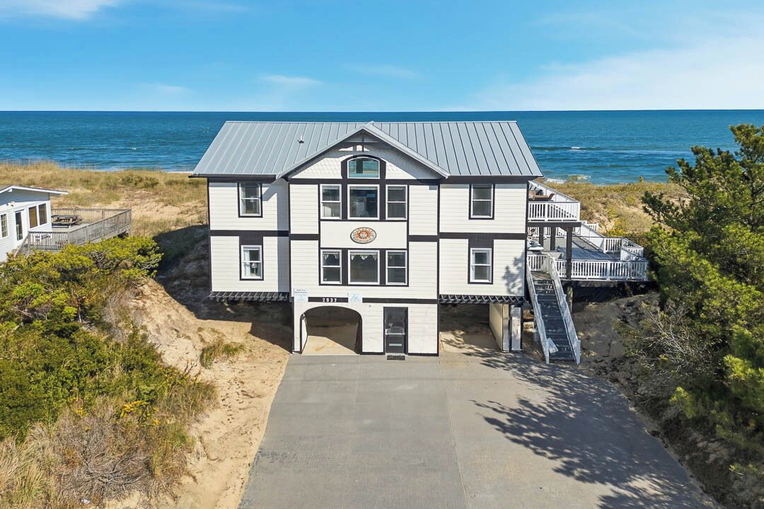 A two-story building with a balcony, a front entrance, and a view of the ocean.