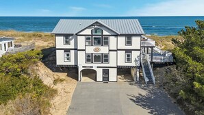 A two-story building with a balcony, a front entrance, and a view of the ocean. - Anthem of the Sun | Oceanfront | Private Pool and Hot Tub (Virginia Beach)