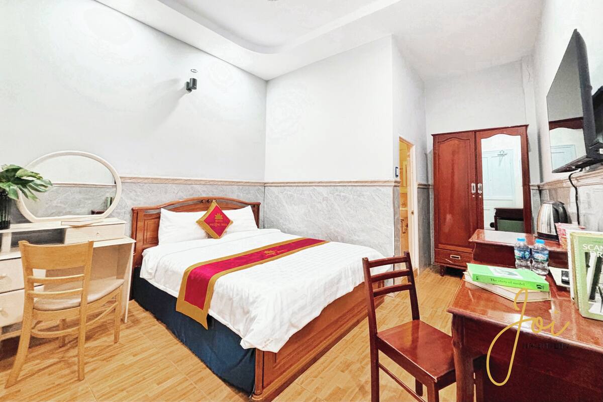 Ein Hotelzimmer mit Bett, Holztisch, Stuhl und Spiegel.